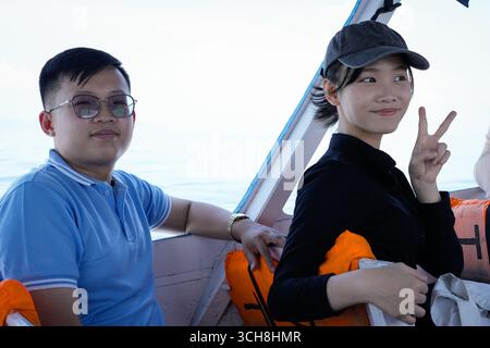 amici sorridenti che si godono un rilassante giro in barca con il paesaggio blu dell'oceano Foto Stock