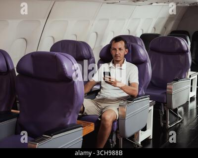 Passeggero seduto da solo in una cabina dell'aereo quasi vuota Foto Stock