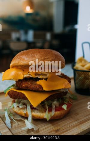 doppio hamburger con uova, formaggio e patatine fritte su tavola di legno Foto Stock