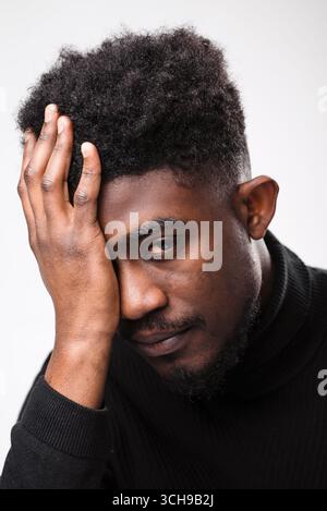 Faccia da vicino di un giovane uomo nero triste Foto Stock