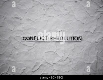 Pezzo di carta arricciato con Words Conflict Resolution su uno sfondo strappato di pezzi di carta bianca Foto Stock