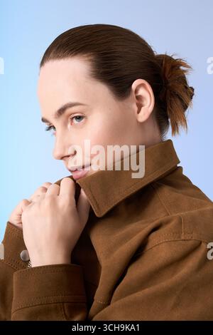 Una giovane donna con un'acconciatura chic si posa con sicurezza indossando un outfit alla moda. Foto Stock