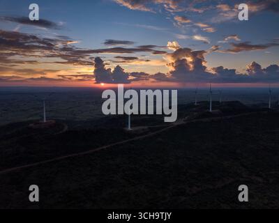 Vista aerea delle turbine eoliche alte sullo sfondo di un tramonto infuocato, che dipinge il cielo con sfumature di arancione e viola, Hosur, Karnataka, India. Foto Stock