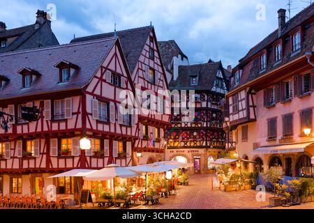 Case illuminate in legno al crepuscolo nel centro storico di Colmar, Alsazia, Francia Foto Stock