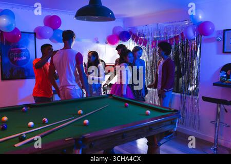 Diversi adolescenti festeggiano a casa, si divertono con palloncini e biliardo. festeggiamenti, adolescenti diversi, amici diversi, tempo libero, intrattenitori Foto Stock