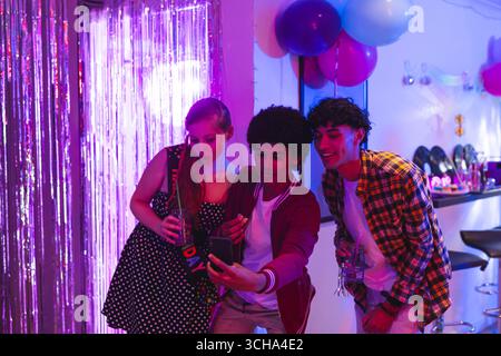 I tuoi amici più eterogenei scattano selfie alla festa di compleanno con palloncini colorati, a casa tua. Celebrazione, amicizia, gioventù, divertimento, allegro, sorride Foto Stock