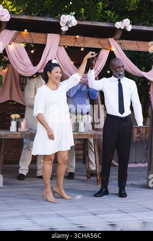 Al matrimonio, coppie di anziani che ballano con gioia durante la festa in giardino sotto il pergolato decorato. Anziani, romanticismo, felicità, in giardino, festivi, Foto Stock
