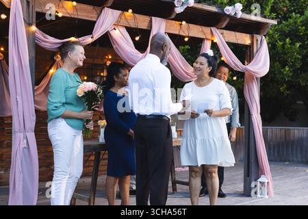 Al matrimonio, coppia di anziani e diversi sorridenti che si scambiano i voti in giardino con amici anziani. matrimonio, felicità, in giardino, matrimonio, anziani, Foto Stock