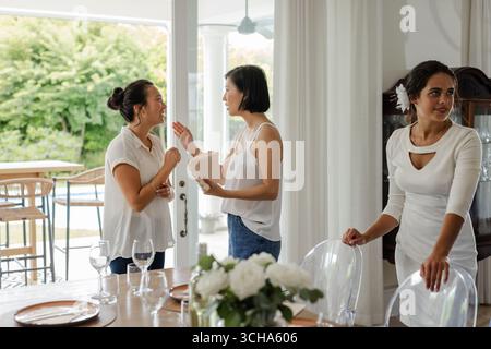Preparate il tavolo da pranzo, le donne chiacchierano e organizzano piccole feste di nozze informali, a casa. evento, preparazione, decorazione, tempo libero, con Foto Stock
