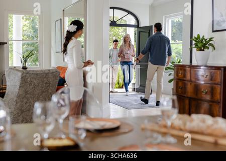 Accogliendo gli ospiti a casa, la coppia sorridente che partecipa a una piccola cerimonia di nozze informale, a casa propria. felicità, ospitalità, romanticismo, gioia, stile di vita, cavolo Foto Stock
