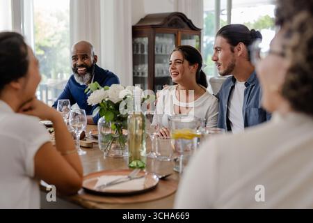 Amici che si divertono a conversare intorno al tavolo da pranzo durante una piccola cerimonia di nozze informale, a casa. amicizia, riunione, brindisi, ricevimento, evento, ha Foto Stock