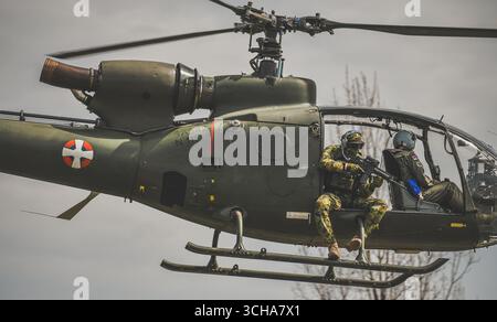 Elicottero militare a gazzella con pilota visibile e soldato delle forze speciali armati con un fucile automatico Foto Stock