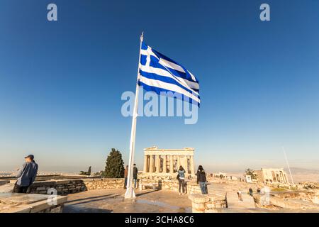 Atene, Grecia. La gigantesca bandiera greca che sventola all'Acropoli con il Partenone sullo sfondo, vista iconica sotto un caldo cielo blu Foto Stock