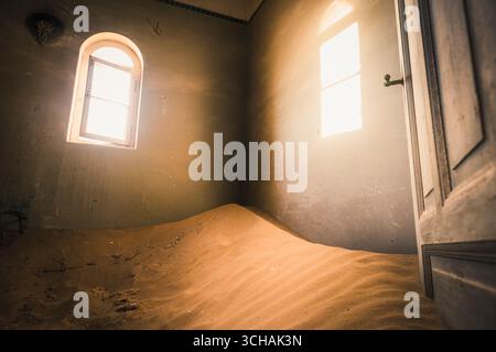La luce del sole entra in una stanza piena di sabbia a Kolmanskop Foto Stock