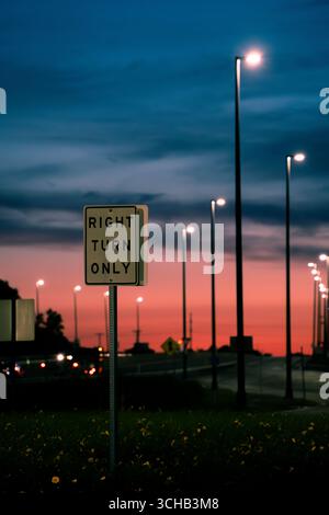 Cartello stradale "Right Turn Only" (solo svolta a destra) con semafori al tramonto. Foto Stock