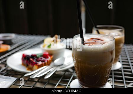 Primo piano di caffè ghiacciato con rivestimento in polvere di cacao, servito con dessert assortiti su un tavolo da caffè a Kyoto, Giappone. Foto Stock