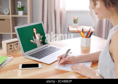 Concetto di e-learning. Studente che ha una video chat online con l'insegnante tramite laptop alla scrivania, primo piano Foto Stock