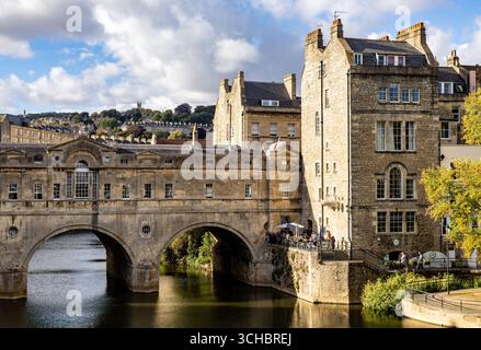 Storico Pulteney Bridge a Bath, Inghilterra, che attraversa il fiume Avon con la classica architettura georgiana e lo sfondo blu del cielo Foto Stock