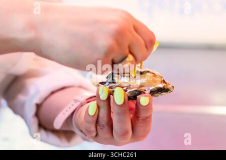 Primo piano di una donna che tiene in mano ostriche appena aperte mostrando interni naturali in una vista dettagliata Foto Stock