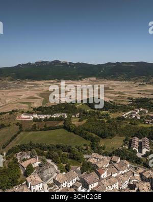 Veduta aerea dei tetti in terracotta che scendono lungo la collina, in contrasto con la valle verdeggiante e le montagne lontane, Pescocostanzo, Abruzzo, Italia. Foto Stock