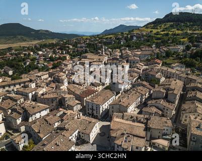 Vista aerea dell'antica città con tetti in terracotta annidati tra dolci colline verdi e montagne lontane, un arazzo senza tempo di fascino rustico, Pescocostanzo, Abruzzo, Italia. Foto Stock