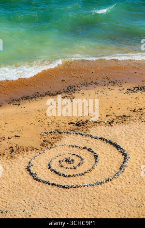 Una spirale di pietre preparate sulla spiaggia da un turista Foto Stock