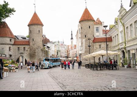 Torri storiche della porta Viru e piazza acciottolata nella città vecchia di Tallinn con turisti e treno turistico Foto Stock