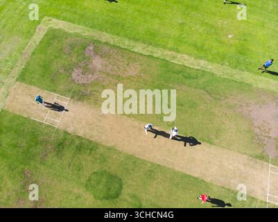 Squadre di cricket maschili diverse che camminano sul campo centrale in un campo sportivo con ceppi di wicket e gesso. Sport, lavoro di squadra, attività all'aperto, atletica, attività ricreative, s Foto Stock
