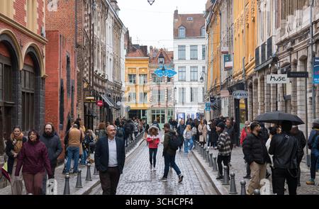 Lille, Francia. Turisti non identificati e gente del posto fanno shopping in "Rue de la Monnaie" in una giornata di pioggia. È una delle strade più antiche della città. Foto Stock