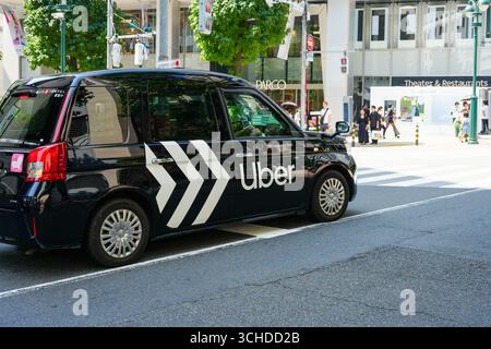 Shibuya, Tokyo, Giappone - 30 agosto 2025: Veicolo Uber nero a Tokyo con gente del posto alla moda e turisti nelle vicinanze, catturando la mobilità moderna e la moda urbana Foto Stock