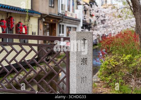 I ciliegi fioriscono completamente lungo lo storico canale del fiume Takase nel quartiere primaverile di Kiyamachi. Kyoto, Giappone. Foto Stock