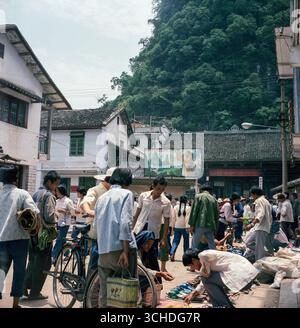 Un mercato di strada a Yangshuo, Guilin, Cina nel 1986. Il poster sta incoraggiando una politica per un solo bambino, soprattutto le ragazze. L'infanticidio era abbastanza comune allora Foto Stock