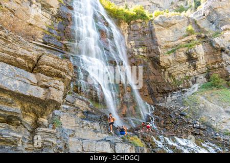 Provo, Utah, USA - 1 settembre 2025: I visitatori si riuniscono alla base delle Bridal Veil Falls mentre diversi ruscelli d'acqua cadono lungo la ripida parete rocciosa. Foto Stock