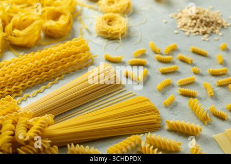 Diverse forme di pasta disposte su una superficie, che mostrano la tradizione culinaria italiana Foto Stock