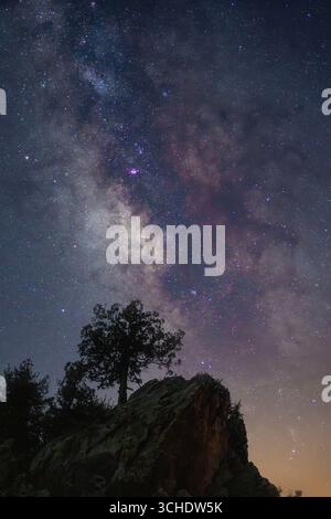 Cielo stellato notturno con la via Lattea sopra la silhouette rocciosa Foto Stock