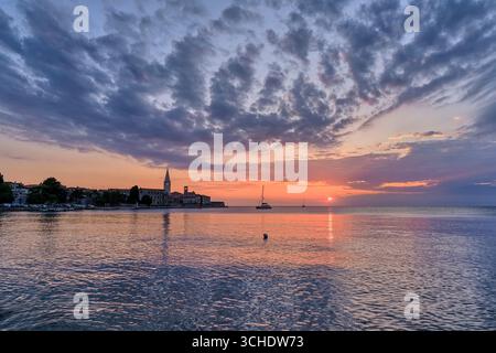 Case nella città costiera di Poreč e il campanile della basilica euforica, viste sopra le acque del Mar Mediterraneo al tramonto. Foto Stock
