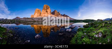 Vista panoramica delle facce nord delle tre Cime di Lavaredo nel Parco Nazionale delle tre Cime al tramonto, riflessa in un piccolo lago. Foto Stock