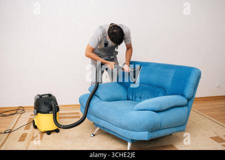 Ampia scelta di addetti ai servizi di pulizia professionali per rimuovere sporco e macchie dal divano imbottito blu utilizzando un aspirapolvere aspirapolvere per aspirapolvere Foto Stock