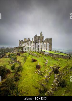 Vista aerea della sagoma rocciosa della Rocca di Cashel si erge su un cielo lunare, abbracciato da vibranti colline verdi., Cashel, Contea di Tipperary, Irlanda. Foto Stock