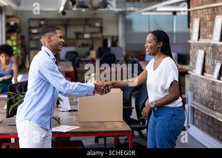 Stringere la mano, diversi colleghi sorridono e collaborano in un ufficio moderno Foto Stock