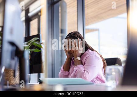donna in ufficio che sembra stressata mentre lavora al computer Foto Stock