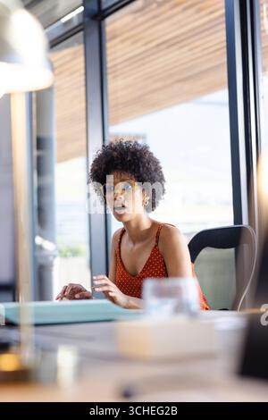 Donna in ufficio sorpresa che guarda un notebook, indossa occhiali e polka dot top, copia spazio Foto Stock