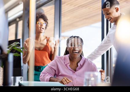 colleghi diversi che celebrano il successo in un ufficio moderno, sorridenti e gioiosi Foto Stock