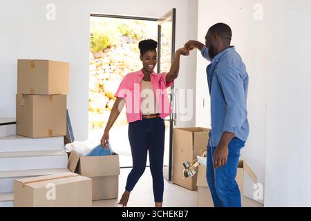 Coppia che celebra la nuova casa, ballando gioiosamente tra i box mobili in salotto Foto Stock