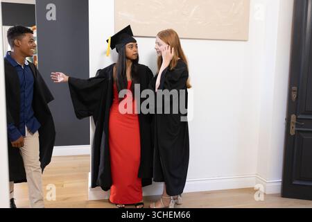 Laureati in berretti e abiti festeggiando insieme in corridoio Foto Stock