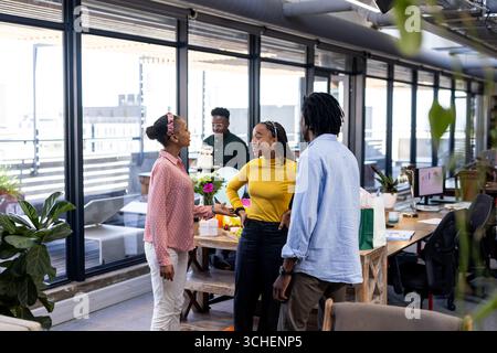 Colleghi diversi che collaborano e discutono idee in un ufficio moderno con grandi finestre Foto Stock
