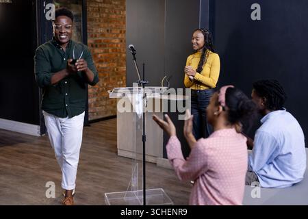 Diversi professionisti applaudono il collega dopo la presentazione in un ambiente moderno di ufficio, spazio di copia Foto Stock