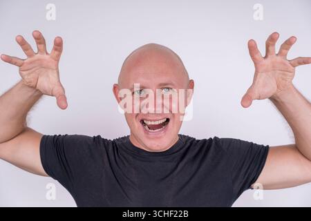 Ritratto di un uomo calvo aggressivo, al chiuso, primo piano. Foto ravvicinata di un uomo calvo caucasico che guarda direttamente la fotocamera. Concetto di persone e stile di vita Foto Stock