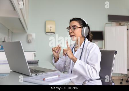 La dottoressa matura degli anni '60 conduce una consultazione virtuale tramite videocall Foto Stock