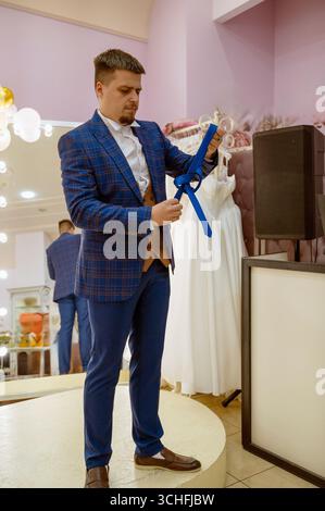 Giovane uomo con cravatta blu. L'uomo si erge alto nel negozio di abiti da sposa. Foto di alta qualità Foto Stock